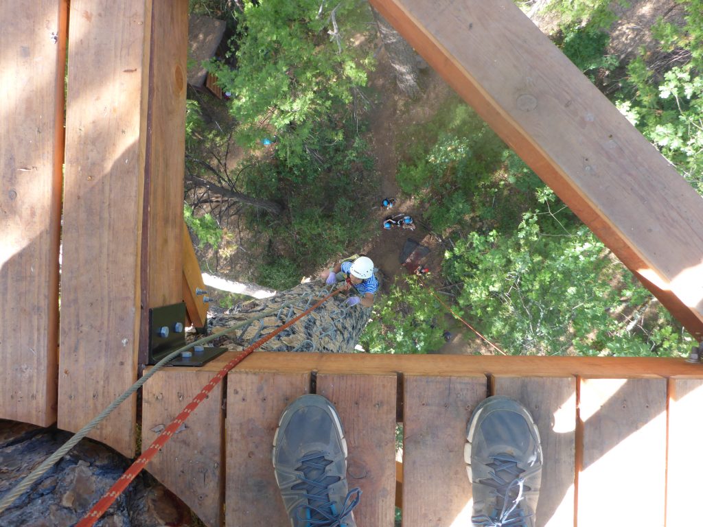 A person climbing a rope, enjoying one of the exciting family camp activities.