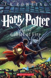 Illustrated cover of Harry Potter and the Goblet of Fire showing Harry flying on a broomstick clutching a golden egg, pursued by a fierce black dragon, with a cheering crowd and stadium in the background.