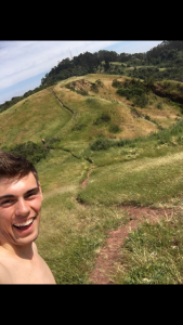 A man taking a selfie in a grassy hill.