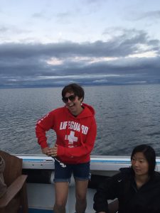 A woman in a red sweatshirt and sunglasses on a boat.