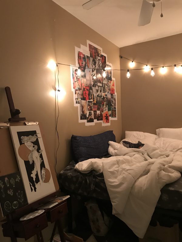Easel with art on left, with bed in center, and overhanging lights