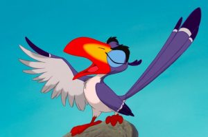 A colorful animated hornbill bird with blue and white feathers, a large orange and yellow beak, and outstretched wings stands on a rock against a clear blue sky.