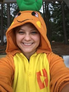 Dani in a carrot onsie with pine trees in the background.