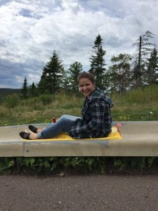 Dani on an alpine slide with greenery and trees in the background.