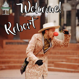 A person in a patterned suit, hat, and red clown nose gestures excitedly outdoors. The text reads “Welcome! Robert.” A Camp Augusta logo appears in the top left corner.
